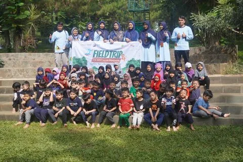 Foto bersama murid TK dengan spanduk fieldtrip di alam terbuka