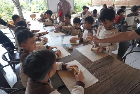 Murid SD mengerjakan kegiatan tangan di meja panjang