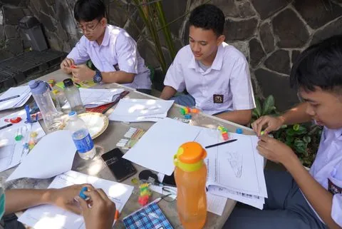 Murid SMA berdiskusi mengerjakan tugas proyek