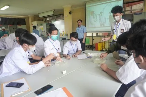 Murid SMA mengerjakan praktikum di laboratorium