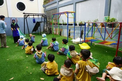 Murid TK bermain di area permainan luar ruang sekolah