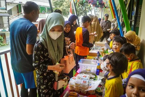 Murid TK melayani pembeli di stan Market Day bersama orang tua