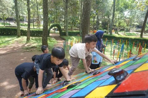 Murid TK menaiki papan luncur warna-warni di area bermain