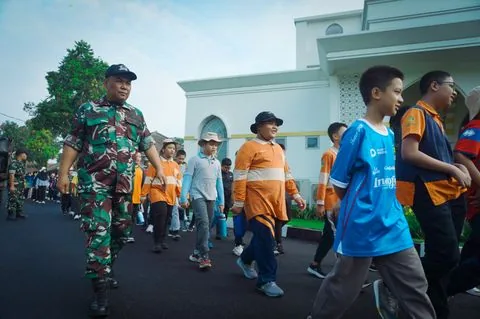 Pelatih memimpin barisan murid SD di lapangan